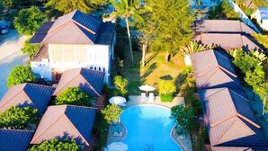 Vista aérea de una zona residencial con varias casas, una piscina y abundante vegetación.