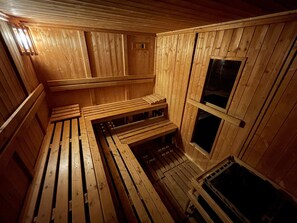 Eine Sauna mit Holzbänken und schrägverdeckter Decke.