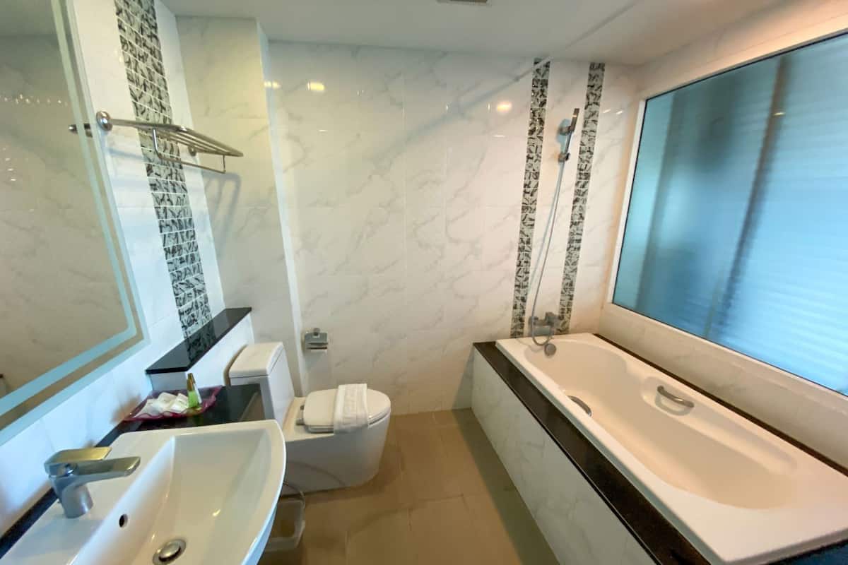 Ein modernes Badezimmer mit einer großen Badewanne, einem Waschbecken, einer Toilette und einer Duschkabine.