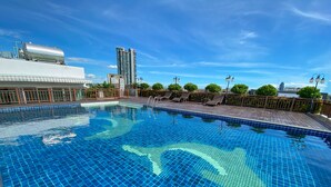 A rooftop swimming pool with clear blue tiles, surrounded by lounge chairs and a wooden deck. - Vareena Palace Hotel (Pattaya)