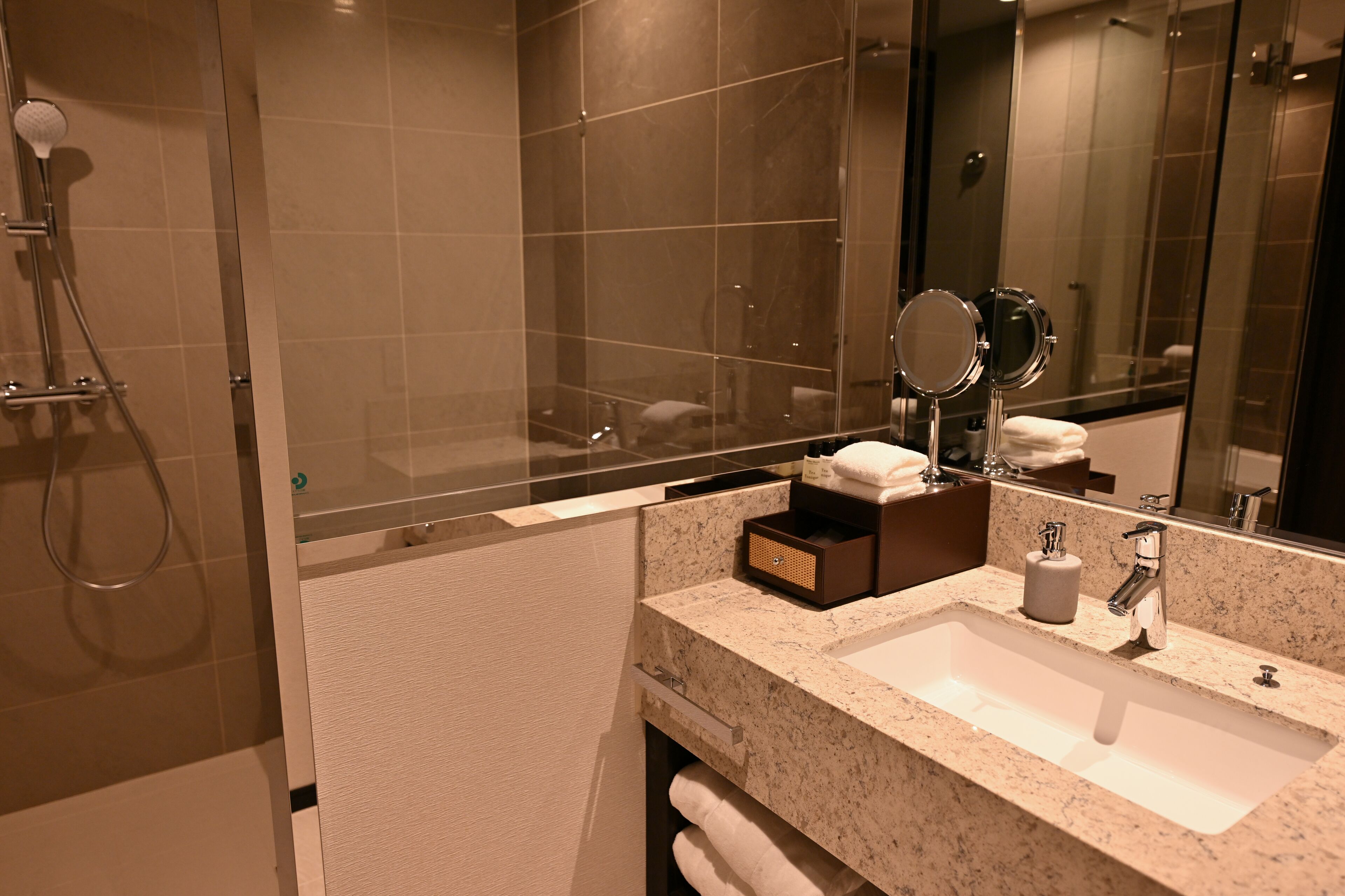 A modern bathroom with a glass-enclosed shower, a sink with a mirror, and a towel rack.