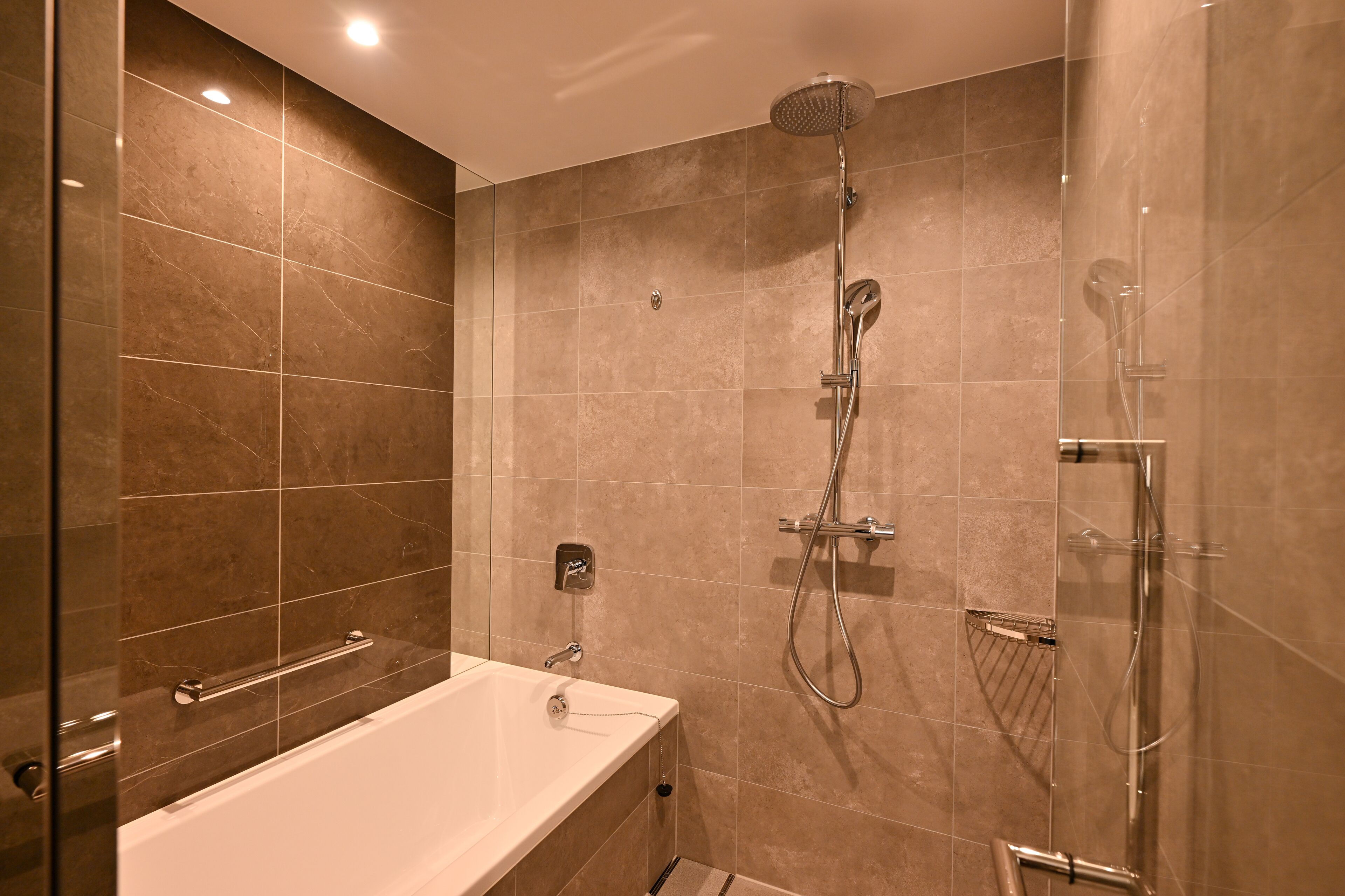 Un baño moderno con bañera, ducha con cabezal de ducha manual y cabina de ducha con paredes de vidrio.