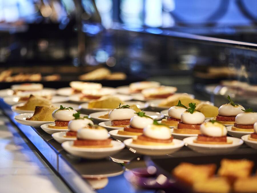 Buffet variado com diversos pratos, incluindo alguns com ovos pochê e guarnições.