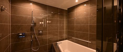 Un baño moderno con bañera, ducha y zona de ducha con mampara de vidrio.