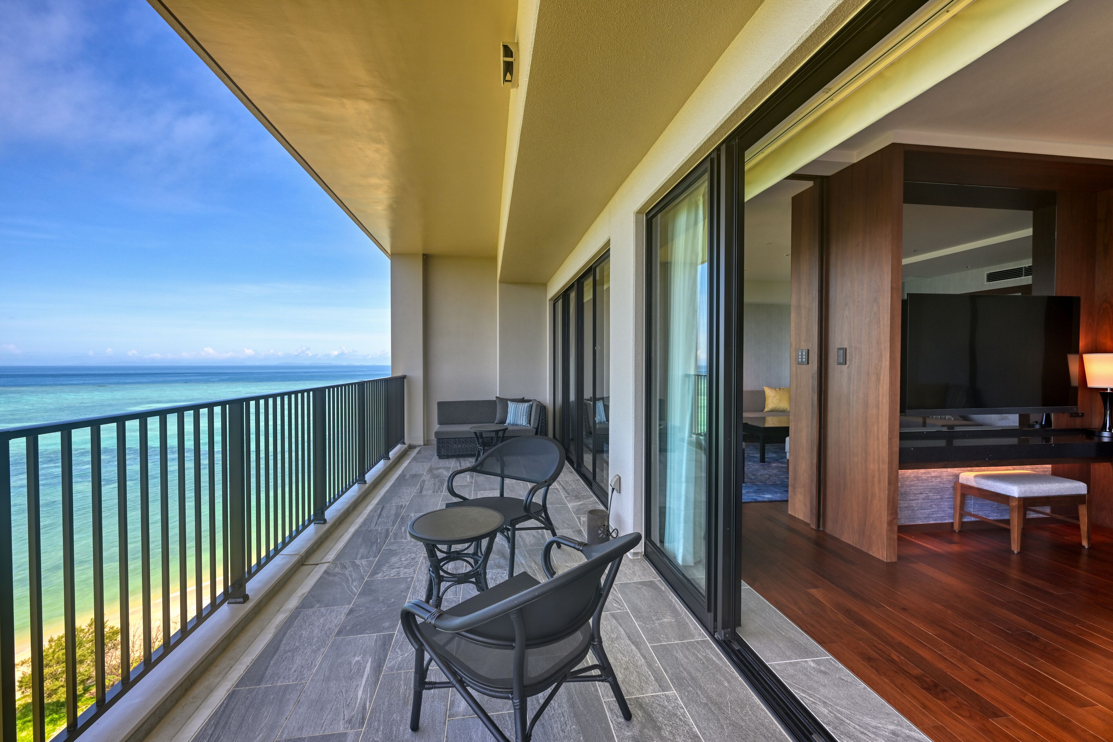 Un balcon avec vue sur l’océan, aménagé avec des chaises et une table, et doté d’un plancher en bois.