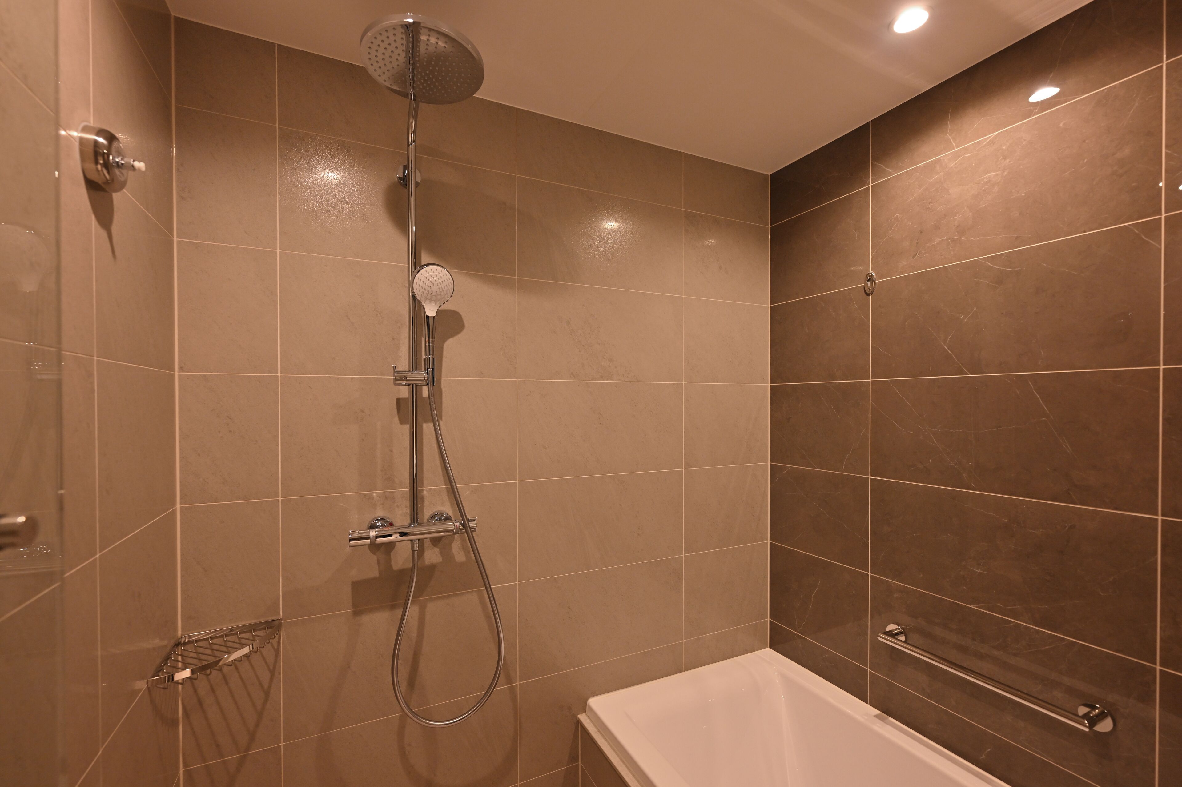 Un baño moderno con ducha, bañera y un perchero para toallas.
