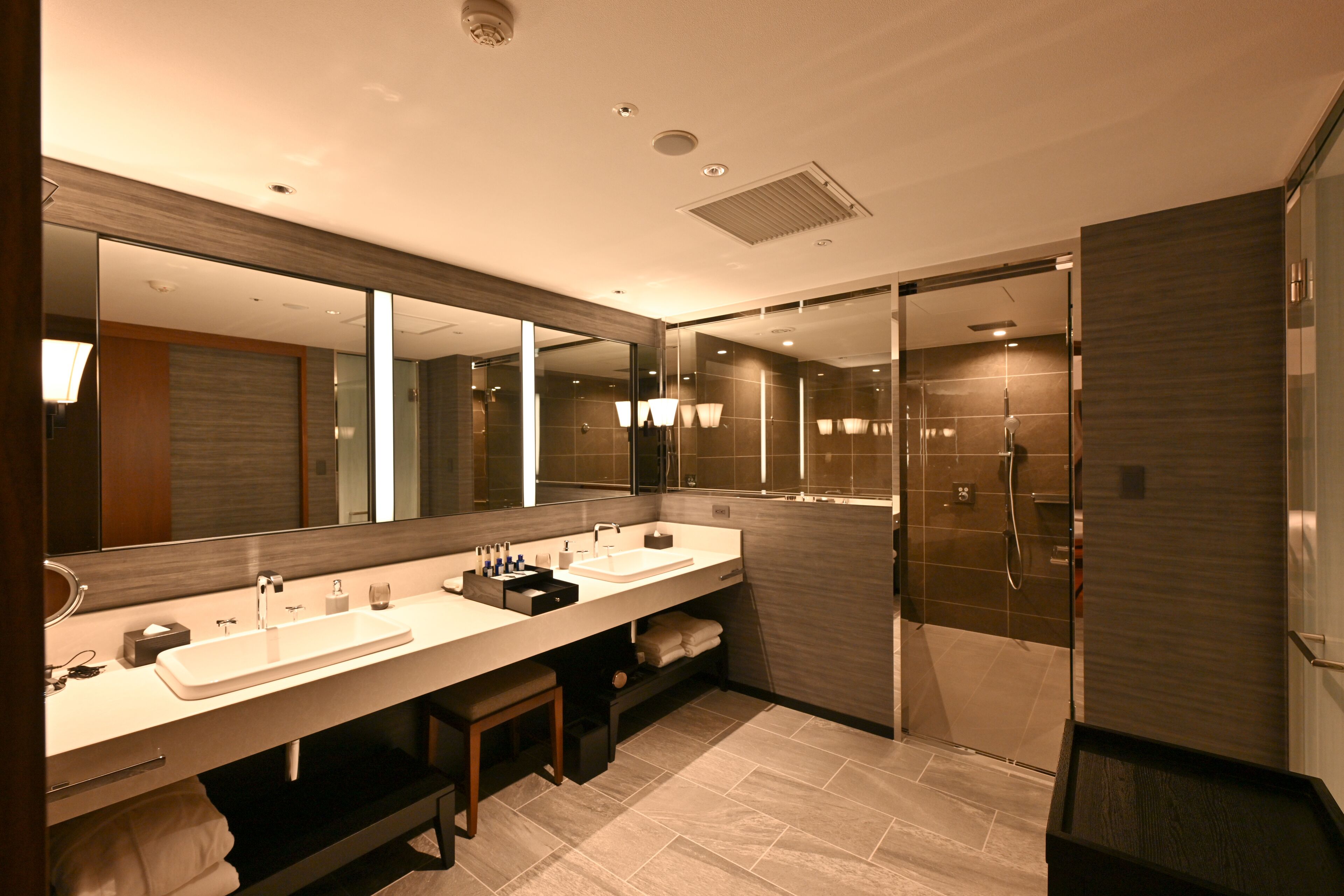 Un baño moderno con dos lavamanos, un espejo grande y una ducha a ras de suelo.