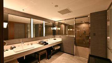 A modern bathroom with two sinks, a large mirror, and a walk-in shower.