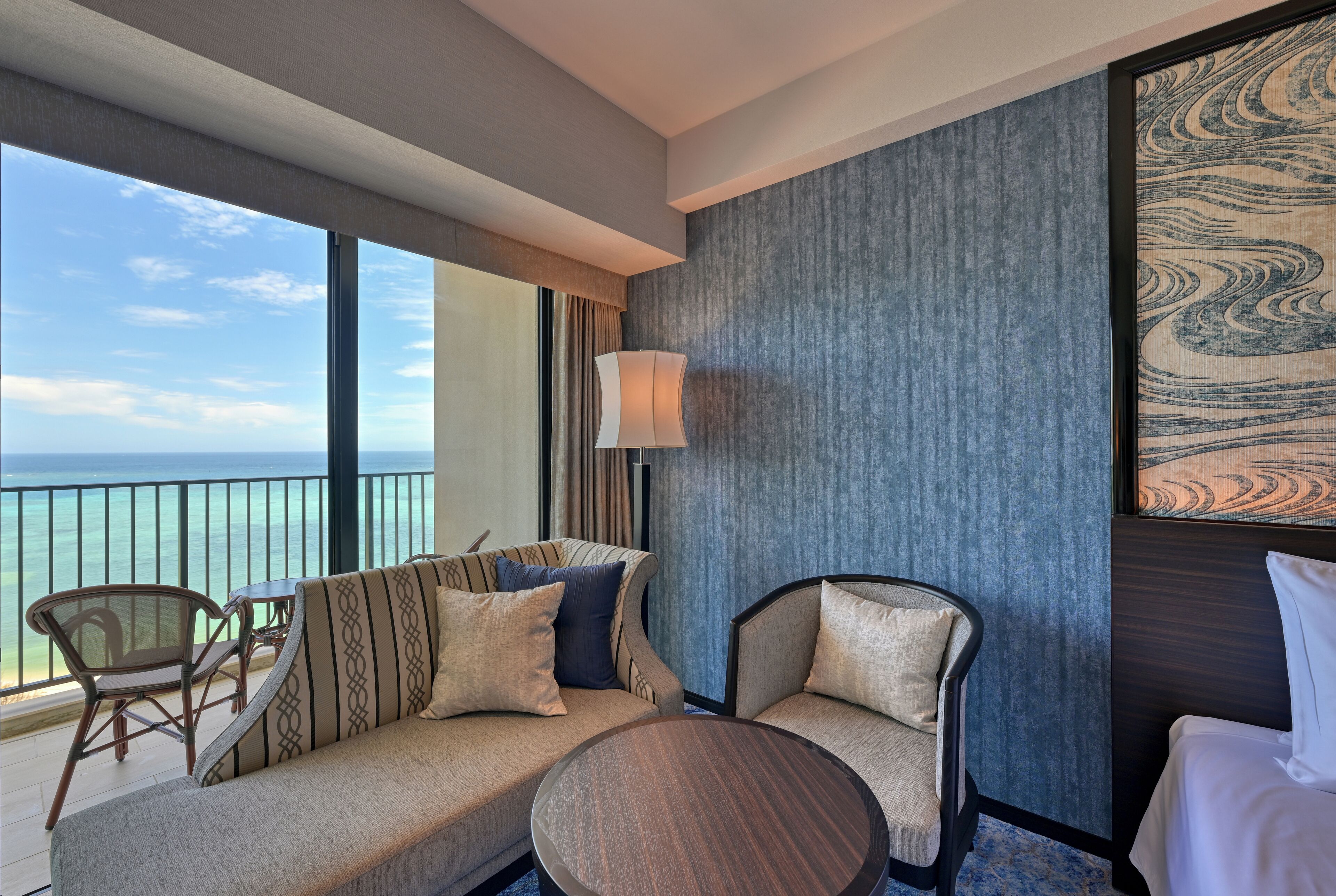 A balcony with a sofa, chairs, and a round table.