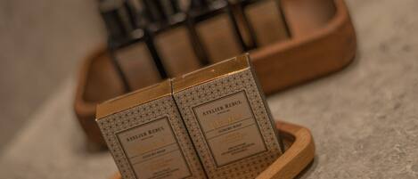 A wooden tray holding two boxes labeled "Atelier Rebul" on a textured surface.