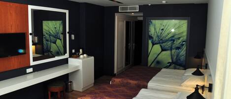 Habitación de hotel con un espejo grande, un escritorio, una silla, dos camas y una lámpara fijada a la pared.