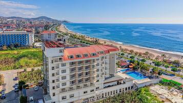 Un hotel moderno con numerosi balconi affacciati su una spiaggia e il mare.