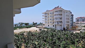 A view of a multi-story building with balconies, surrounded by banana plants.