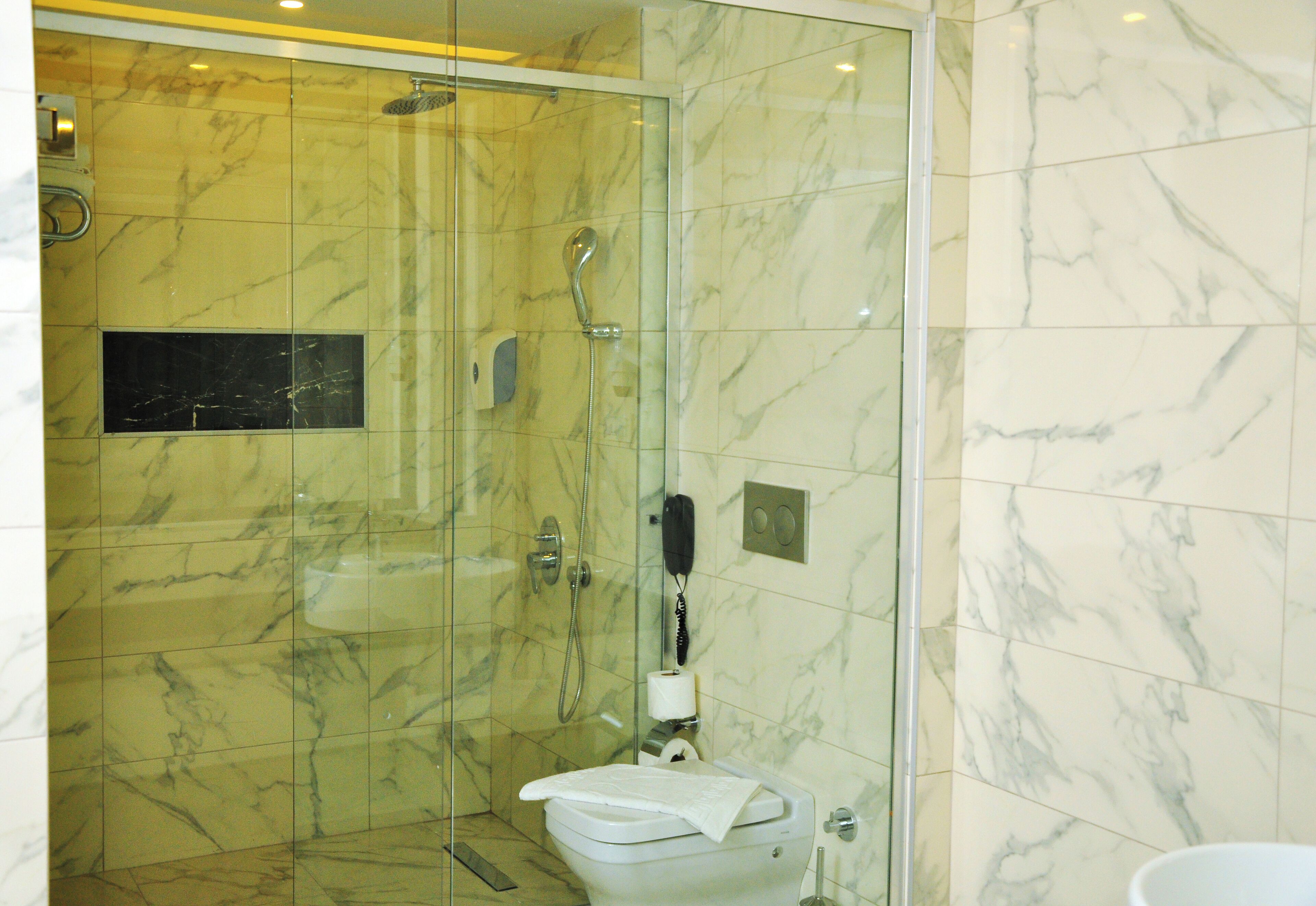 A bathroom with a glass-enclosed shower, a toilet, and a sink.