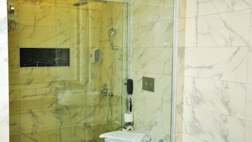 A bathroom with a glass-enclosed shower, a toilet, and a sink.