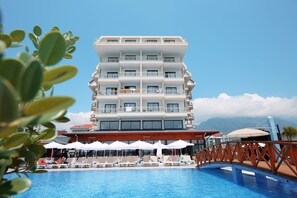 A multi-story hotel with a pool area, including lounge chairs and umbrellas. - SEY BEACH HOTEL &SPA (Alanya)