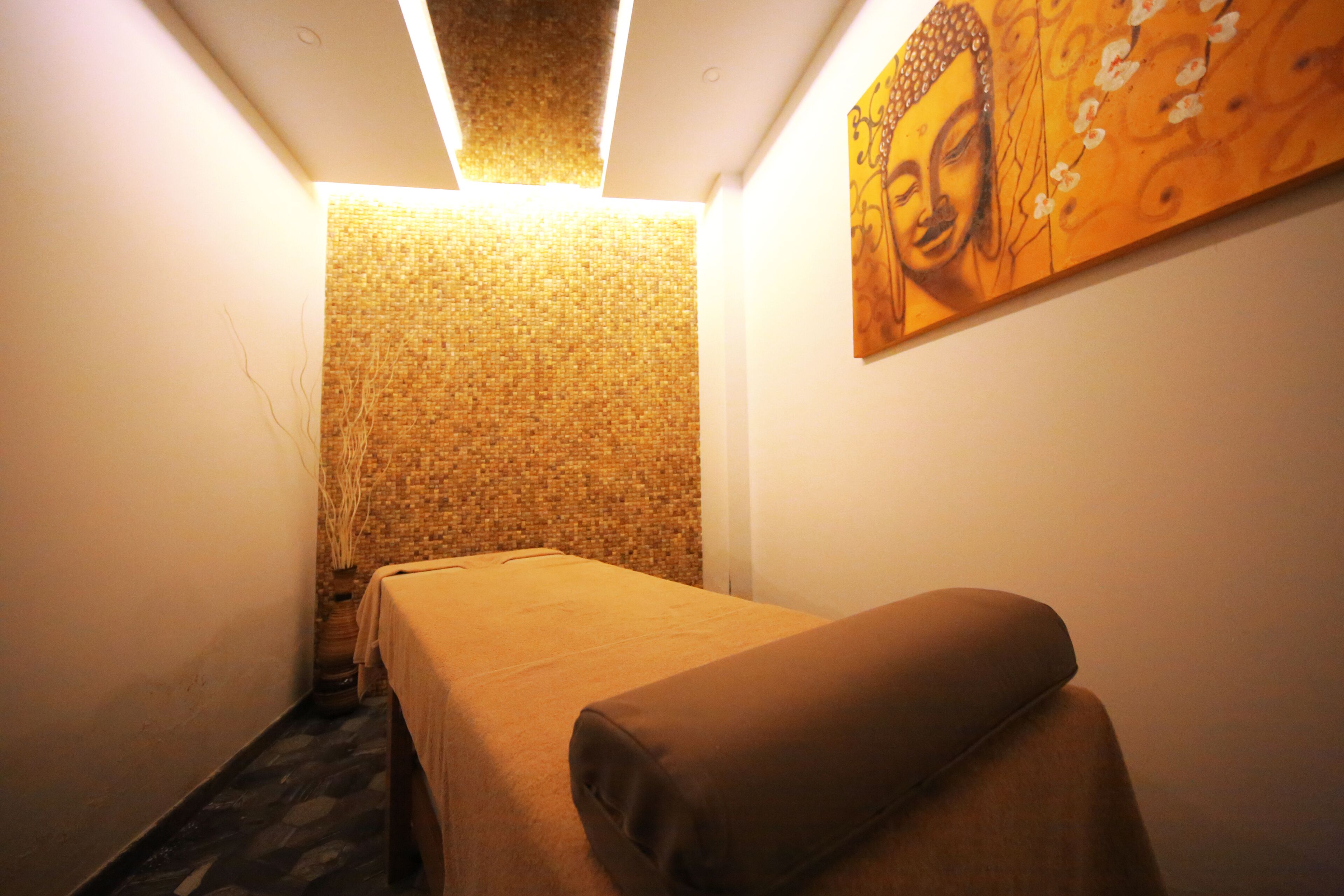 Una habitación con una cama, un muro con textura y un cuadro de Buda.