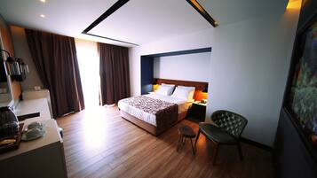 Een hotelkamer met een groot bed, een bureau met een lamp, een stoel en een schilderij aan de muur.