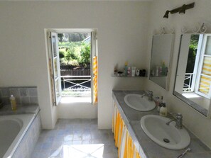 A bathroom with two sinks, a shower, and a window with a view of a garden. - Charming lodging with a garden—perfect for a vacation with family or friends (Auray)