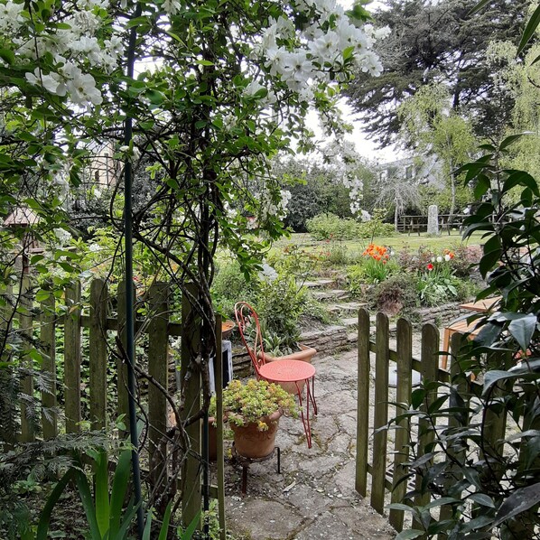 A garden with a wooden gate, potted plants, and a red chair.