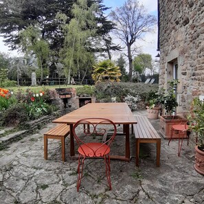 A wooden patio with a table and chairs, surrounded by potted plants and a stone wall. - Charming lodging with a garden—perfect for a vacation with family or friends (Auray)