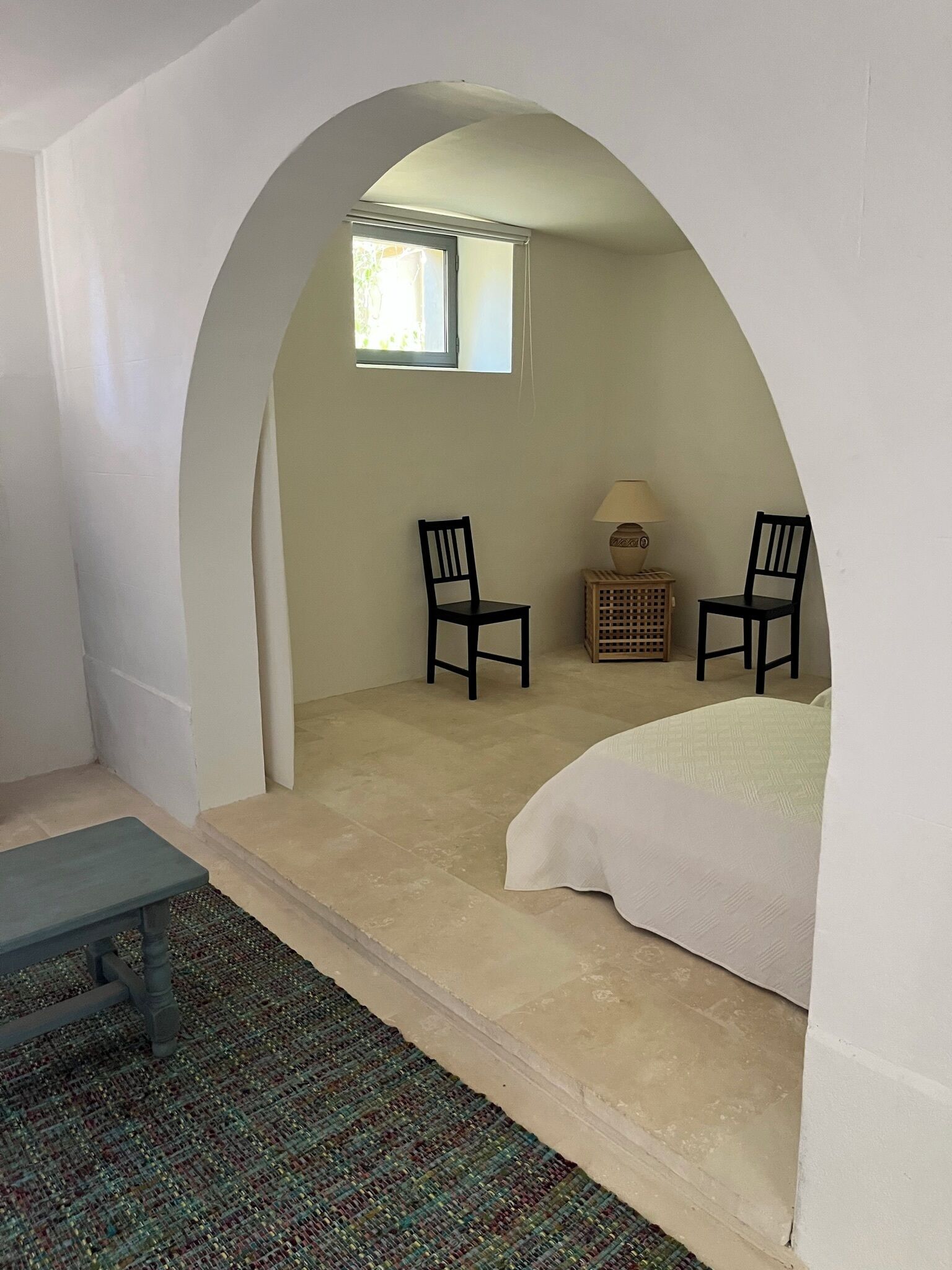 Une chambre à coucher avec un lit, deux chaises, une petite table et une fenêtre.