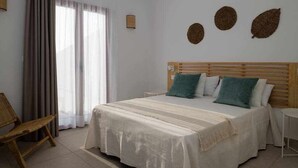 Una camera da letto con un letto, una sedia, un comodino e una finestra con tende.