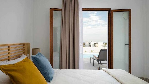 Ein Hotelzimmer mit Bett, Blick auf einen Pool und einer offenen Tür, die nach draußen führt.