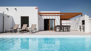 Ein moderner Poolbereich im Freien mit Liegestühlen und einer überdachten Sitzgelegenheit.