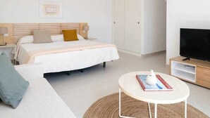 Ein modernes Hotelzimmer mit Bett, Fernseher, Couchtisch und Sofa.