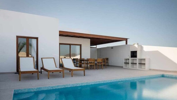Un espace piscine extérieur moderne, doté de chaises longues et d’un ensemble de mobilier de jardin.