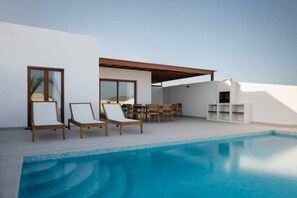 A modern outdoor pool area with lounge chairs and a dining set. - Villa Naira, con Piscina Privada (Playa Blanca (Yaiza))