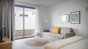 Een moderne hotelkamer met een bank, een bed, een klein tafeltje en uitzicht.