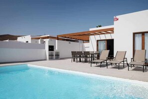 A modern outdoor pool area with lounge chairs and a pergola. - Villa Maialen, con Piscina Privada (Playa Blanca (Yaiza))