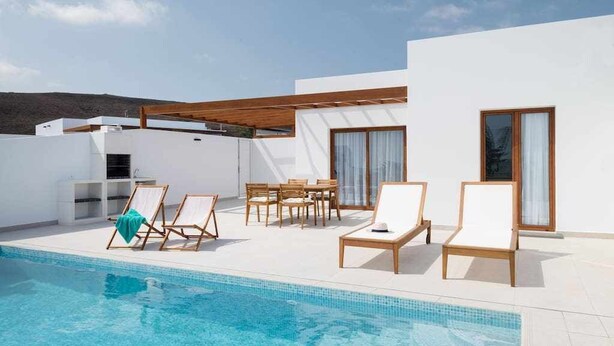Un espace piscine extérieur moderne, doté de chaises longues et d’un ensemble de mobilier de jardin.