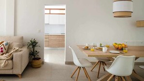 Un salon moderne avec un canapé, une table à manger et des chaises, et une cuisine en arrière-plan.
