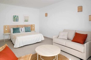 A modern bedroom with a bed, a sofa, a round table, and two wall-mounted lamps.