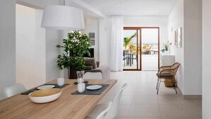 Un espace repas moderne avec une table en bois, des chaises blanches et une grande plante en pot.