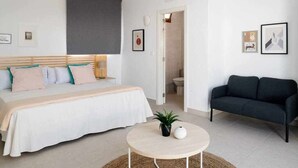 Une chambre à coucher moderne avec un lit, des tables de chevet, une table basse ronde et un canapé de couleur foncée.