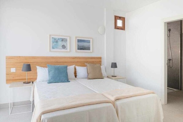 Un letto matrimoniale con testiera in legno, due comodini e un tavolino da notte. Due quadri appesi al muro.