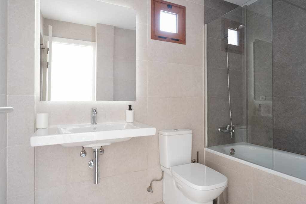 Une salle de bain avec un lavabo blanc, des toilettes et une douche fermée par des parois en verre.