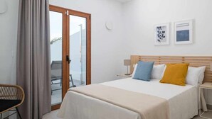 A hotel room with a bed, a chair, a nightstand, and a view through a glass door. - Villa Zaloa, con Piscina Privada (Playa Blanca (Yaiza))