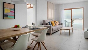 A modern living room with a dining area, a sofa with colorful cushions, and a large window offering a view of the sea. - Villa Zaloa, con Piscina Privada (Playa Blanca (Yaiza))