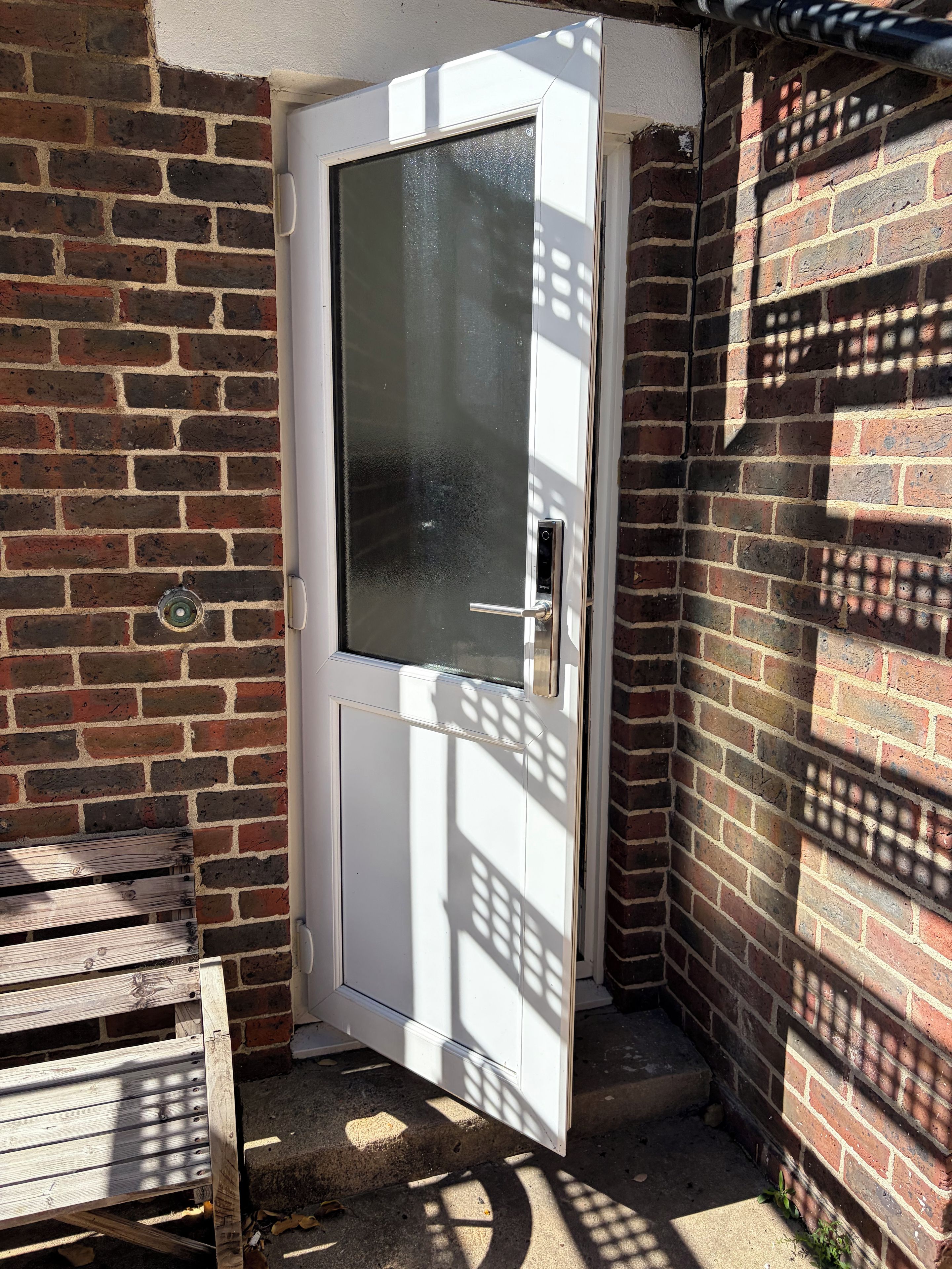 Eine weiße Tür mit Fensterglas, Metallbeschlägen und einem Spion.