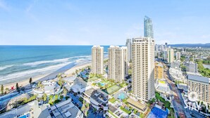 A coastal cityscape with high-rise buildings, including a prominent Novotel hotel, and a beach.