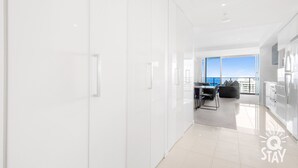 A modern, bright hotel room with a large window offering a view of the sea.