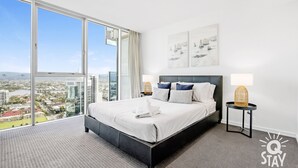 A modern hotel room with a large bed, a view of the city, and a balcony.