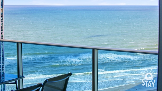 A balcony with a view of the ocean, a chair, and a logo with the text "STAY".