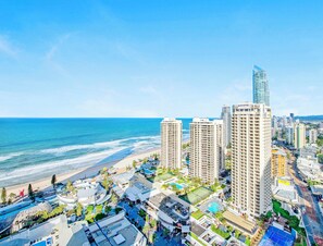 Een kuststadsgezicht met hoge gebouwen, waaronder een opvallend Novotel hotel, en een strand.