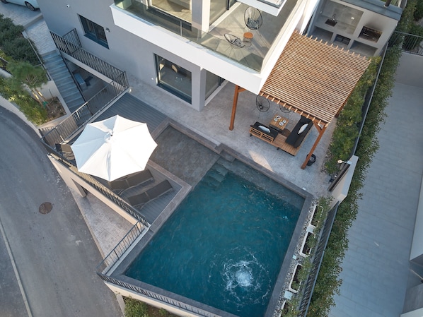 A modern residential building with a rooftop pool, outdoor seating, and a staircase.